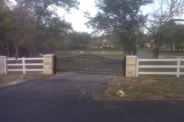Contractor installing a custom steel gate between brick entrance columns in Georgetown, TX