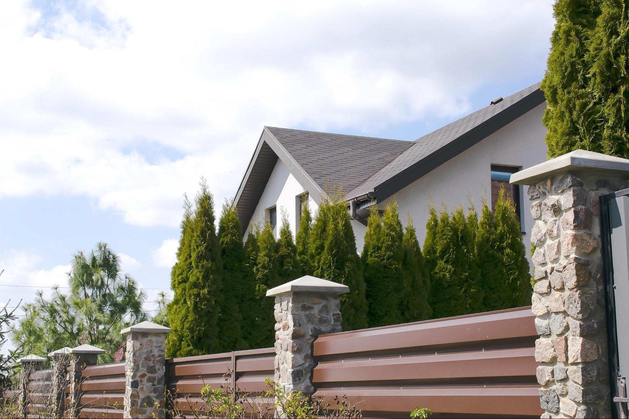Custom Residential Fence Installation Georgetown TX A brown privacy fence featuring custom stone pillars installed outside a residential home, showcasing the personalized masonry and design options available from a Georgetown fence company.