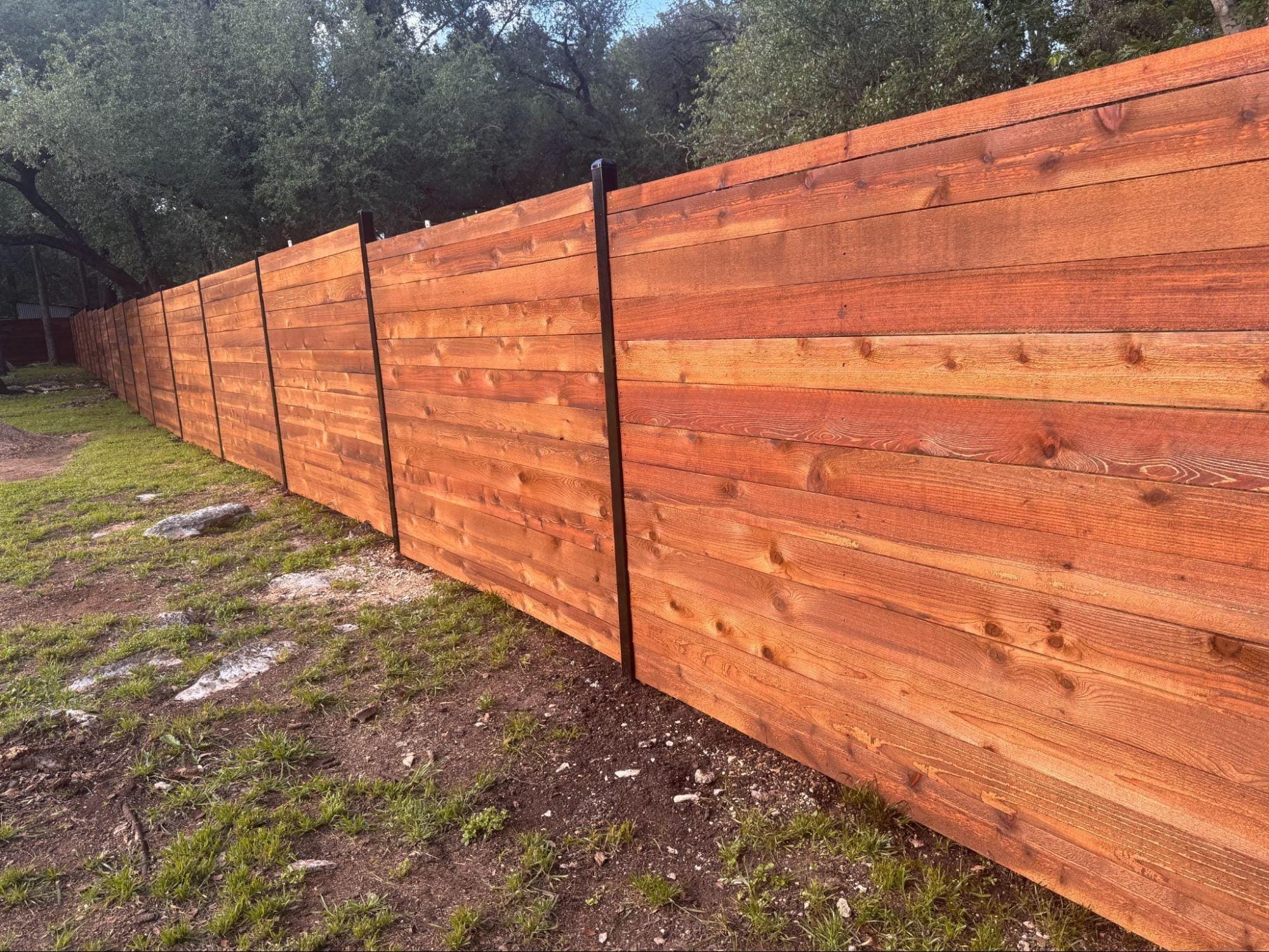 A sleek black aluminum decorative fence surrounding a residential backyard and stone patio, demonstrating high-quality materials that prevent long-term maintenance costs.